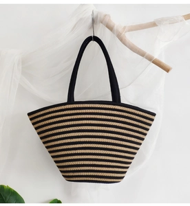 Detail of handwoven black and beige striped cotton rope tote bag hanging on wooden branch