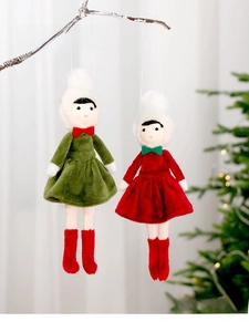Detailed view of two Christmas plush dolls hanging from a branch in a cozy indoor setting