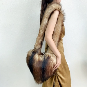 Model wearing a large heart-shaped faux fur crossbody bag in brown and beige tones