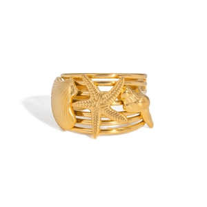 Détail d'une bague marine dorée à plusieurs couches avec breloques étoile de mer et coquillage
