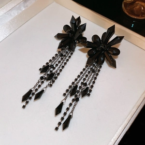 Detail of gothic black crystal fringe earrings with floral cluster on white background