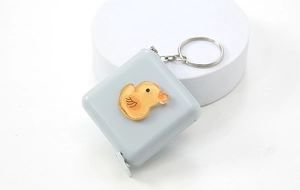 Detail of gray square measuring tape with cute yellow duck ornament on a pedestal