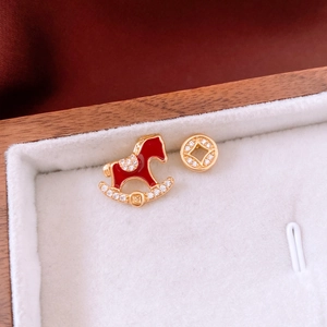 Détail macro de boucles d'oreilles plaquées or 18 carats avec cheval rouge et pièce