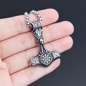 Macro shot of a vintage silver Mjolnir pendant necklace with Viking runes held in hand