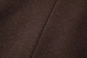 Macro shot of dark brown wool fabric texture and seam detail on long winter coat