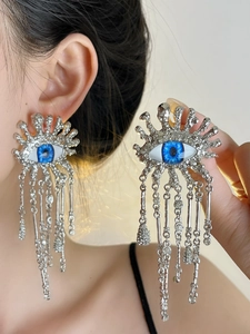 Close-up of evil eye earrings with silver tassels and sparkling white rhinestones