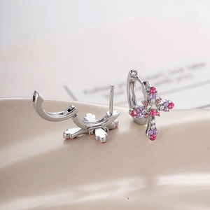 Bohemian silver hoop earrings with a colorful crystal cross pendant on a beige background