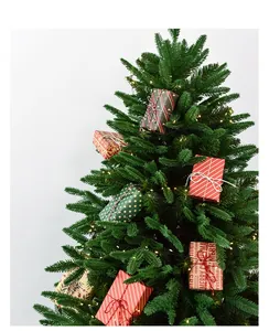 Macro shot of artificial Christmas tree with warm LED lights and mini gift box ornaments
