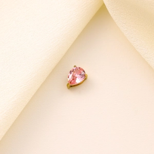 Detail shot of a pear-cut pink zircon stone set in a golden metal pendant on silk