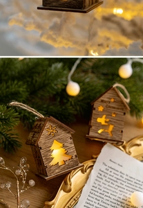Detail of a lighted Christmas wooden house pendant with reindeer and warm LED glow