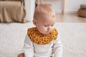 Close-up of baby bib in yellow leopard print made of soft cotton muslin for newborns