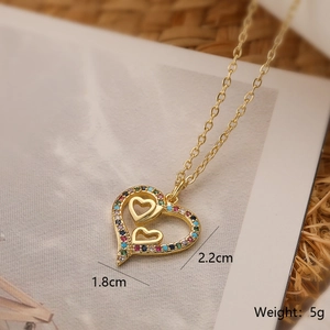 Close-up of gold heart pendant with colorful zircons and size markings of 2.2cm height