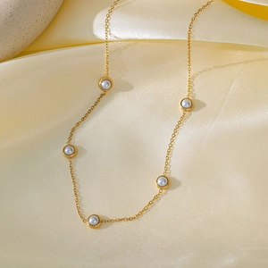 Elegante gouden titanium ketting met vijf ronde witte parels aan een fijne schakelketting