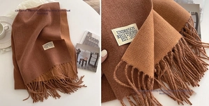 Macro shot of dark brown cashmere-like scarf texture with stylish fringe and minimalist label