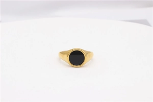 Detailed close-up of a minimalist gold-plated signet ring with a black round inlay