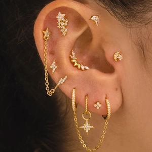 Detailed view of gold ear piercing set with marquise stones, star, and moon charms