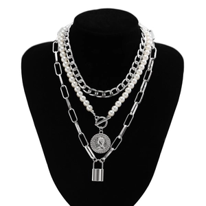 Silver baroque pearl layered necklace with coin and lock charms on black mannequin