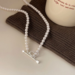 Elegant 925 silver pearl necklace with Cupid arrow and heart toggle clasp on warm background