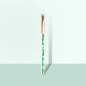 Detail of eyeshadow brush with rose gold ferrule and green sequin filled handle