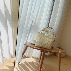 Detail of floral quilted mini tote bags resting on a wooden table in sunlight