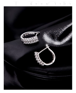 Macro shot of silver U-shaped earrings with double row paved zircons on black silk