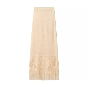 Dettaglio della gonna lunga in maglia beige con nappe a frangia a doppio strato