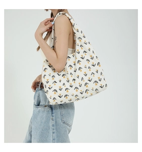 Detail of white corduroy tote bag with yellow tulip pattern shown on shoulder