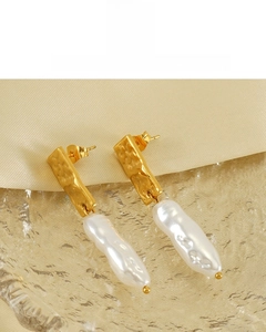 Macro shot of gold hammered metal earrings featuring natural baroque pearl pendants