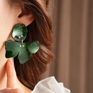 Detail view of a vintage dark green resin flower earring with gold accents and small diamonds