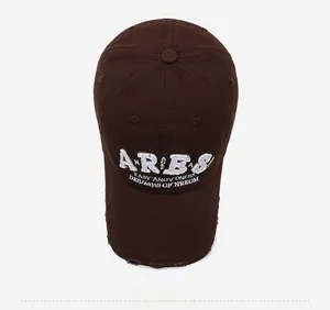 Close-up of ARIES letter embroidery and distressed details on dark brown baseball cap