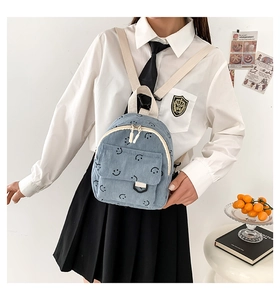 Detail eines hellblauen Cord-Mini-Rucksacks mit Smileys in einem Campus-Ambiente