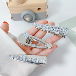 Three elegant silver zircon duckbill hair clips held in hand for a premium styling look