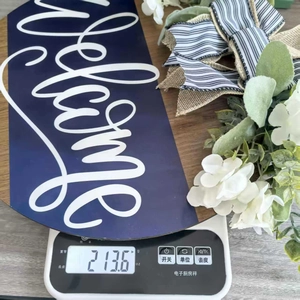 Detail shot showing a 213g lightweight wooden welcome sign with flowers on a scale