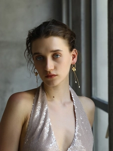 Detail view of 18K gold plated flower earrings with pearls and long tassels on a model
