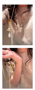 Detail of golden planet pendant with crystals, tiger eye beads and drop pearl on chain