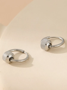 Close-up of silver stainless steel hoop earrings with knurled texture bead charms