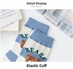 Detailed close-up of blue striped mid-calf socks with cute bear embroidery and elastic cuff