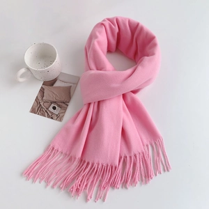 Flat lay detail of pink cashmere-like scarf with twisted tassels and decorative mug