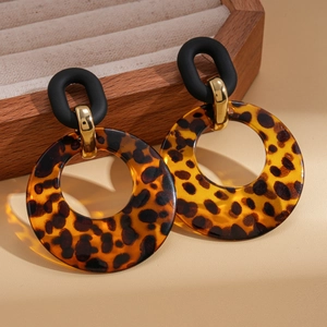 Detail of geometric leopard print acrylic earrings on a wooden jewelry display tray