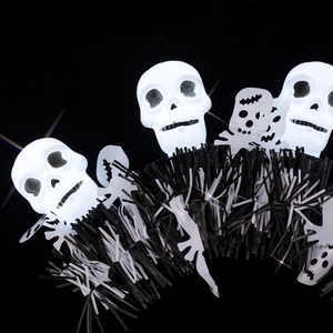 Detail of Halloween tinsel with glowing white skulls and ghost cutouts on black background