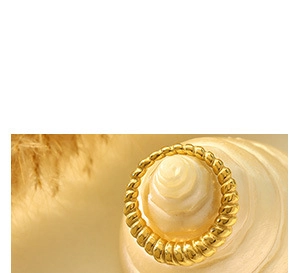 Makroaufnahme von 18K vergoldetem Croissant-Ring aus Edelstahl auf Muschel-Hintergrund