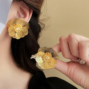 Close-up of gold plated hollow flower earrings featuring a sparkling zircon center stone