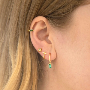 Close-up of gold ear cuff set with emerald green rectangular stones and cubic zirconia studs