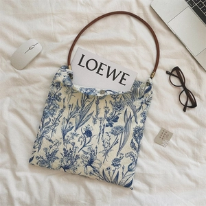 Detail of blue floral porcelain print tote bag on white linen with a leather handle