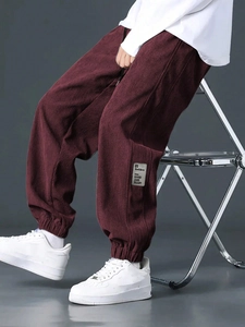 Detail of burgundy corduroy joggers showing the fine ribbed texture and decorative fabric patch