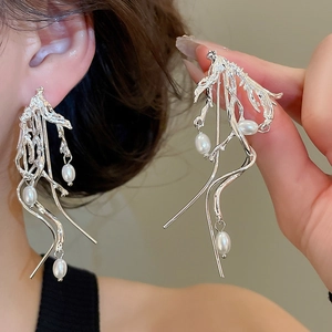 Detailed macro shot of silver vine earrings featuring organic lines and white pearls