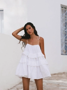 Detail of white tiered ruffle mini dress with delicate spaghetti straps and cotton texture