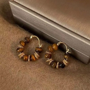 Macro shot of 14k gold-plated hoop earrings with natural brown tiger eye stone beads