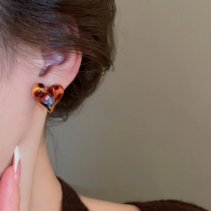 Close-up of heart-shaped leopard print resin earring worn by a model in warm light