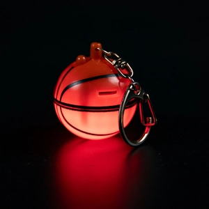 Macro shot of orange basketball keychain with LED red light glowing in dark setting